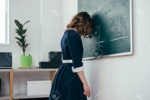 Sad schoolgirl standing in front of blackboard